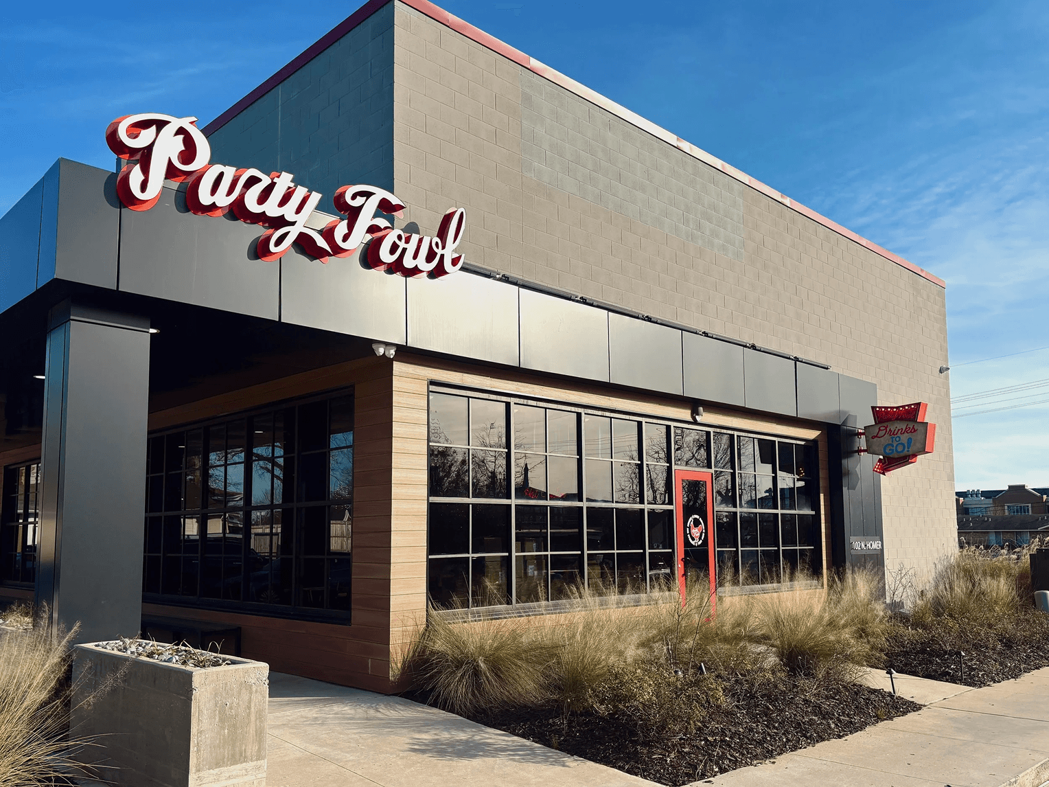 A modern restaurant with a sign reading 'Party Fowl' and a clear blue sky in the background.