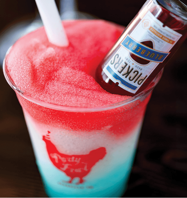 A vibrant, layered slushie with a blueberry liquor bottle and a straw, perfect for a refreshing adult treat.