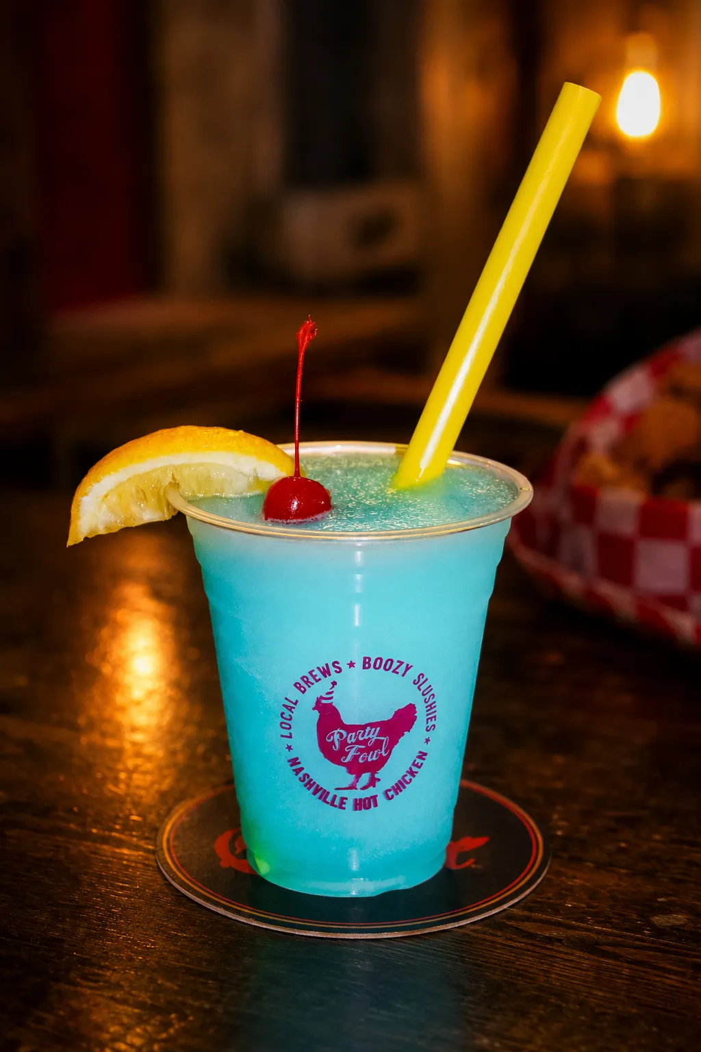 Blue Razz A vibrant blue slushy drink garnished with a cherry and lemon slice, served in a branded cup with a yellow straw.