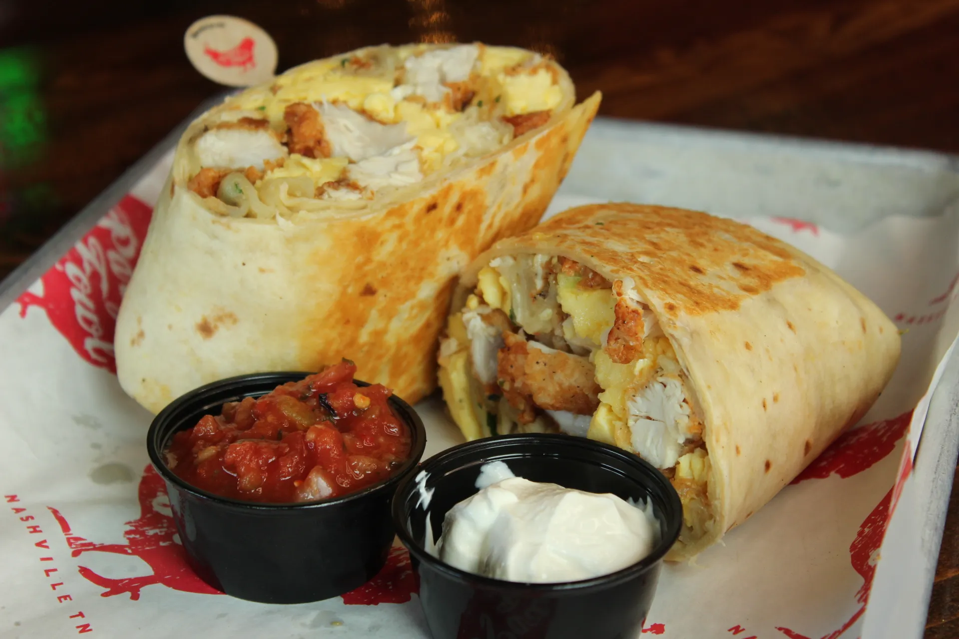 Breakfast Burrito A delicious breakfast burrito filled with scrambled eggs, cheese, and crispy hash browns, served with salsa and sour cream.
