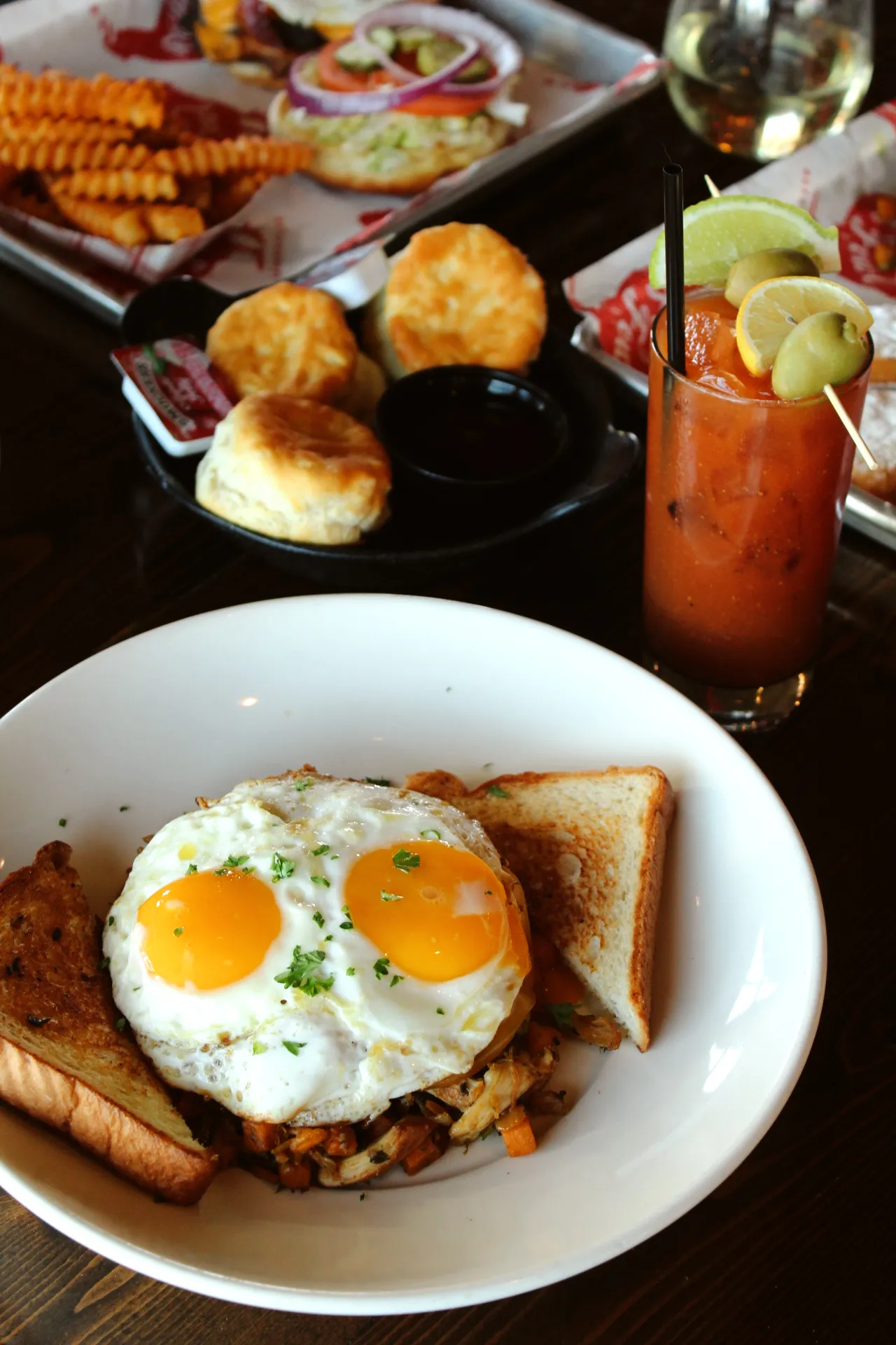 Hash A hearty breakfast featuring two sunny-side-up eggs, toast, and a Bloody Mary garnished with lemon and olives.