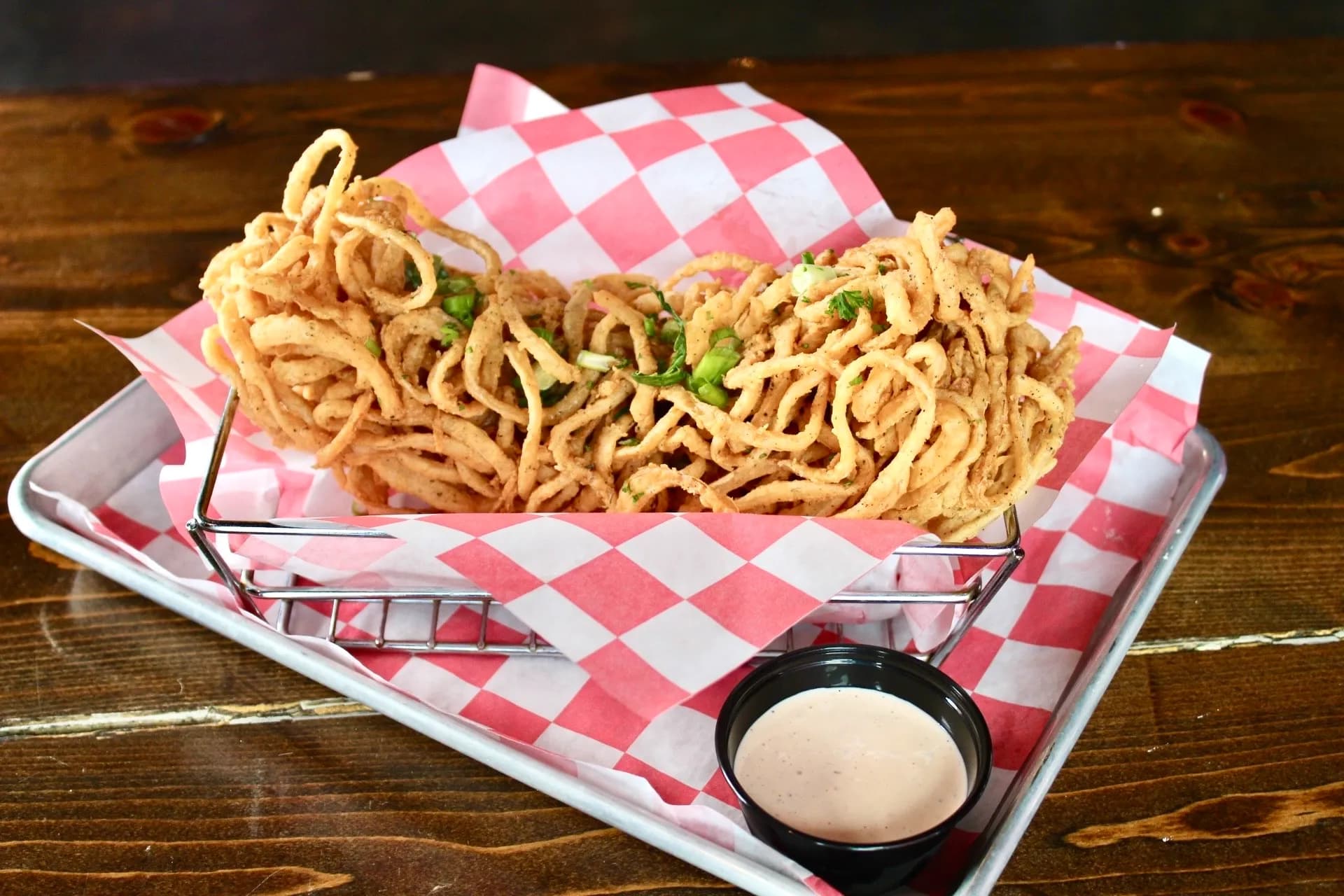 Onion Loaf Deep-fried onion rings served in a basket with a side of dipping sauce.