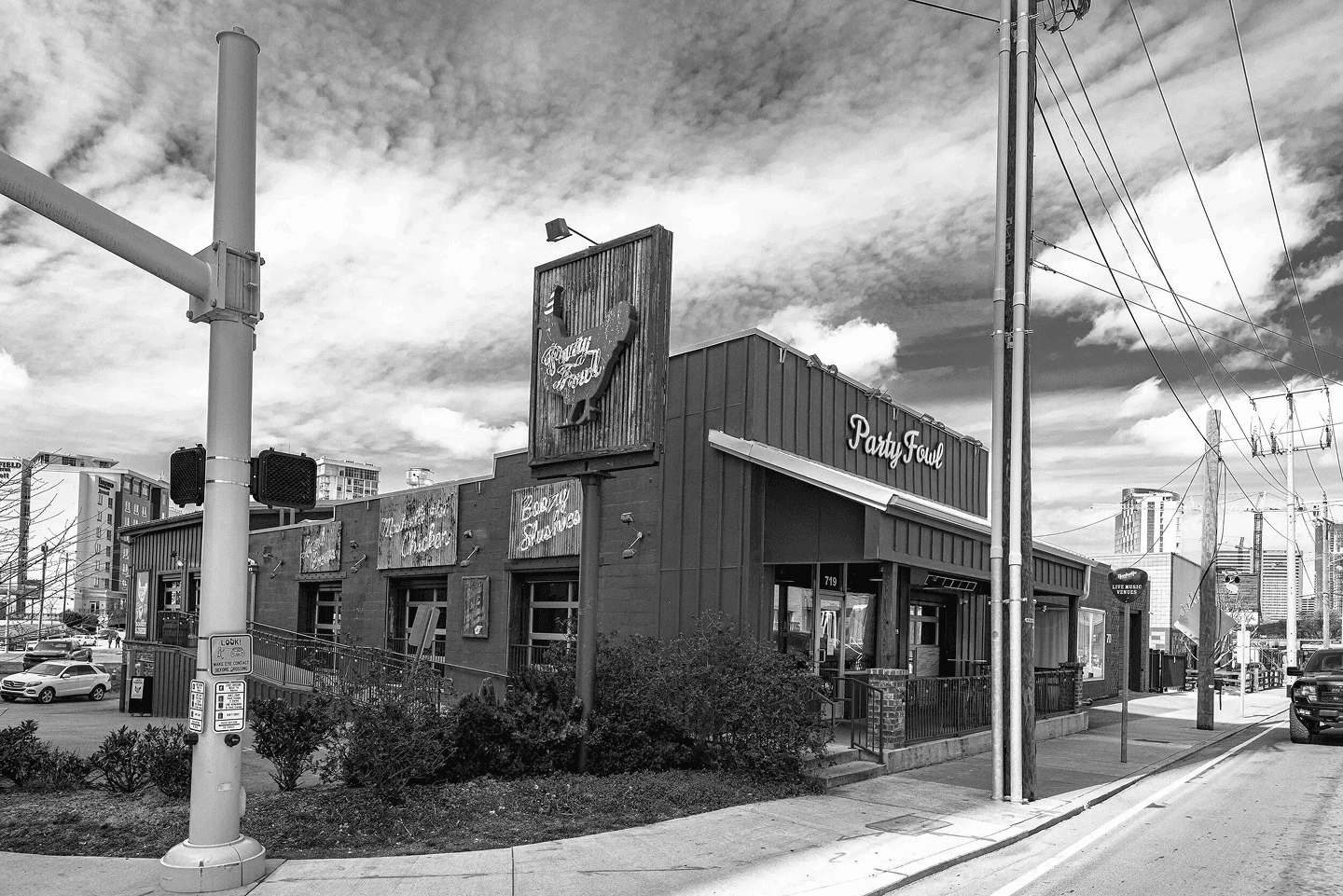 Party Fowl Restaurant A black and white image of a restaurant named 'Party Fowl' with a rustic sign and urban surroundings.