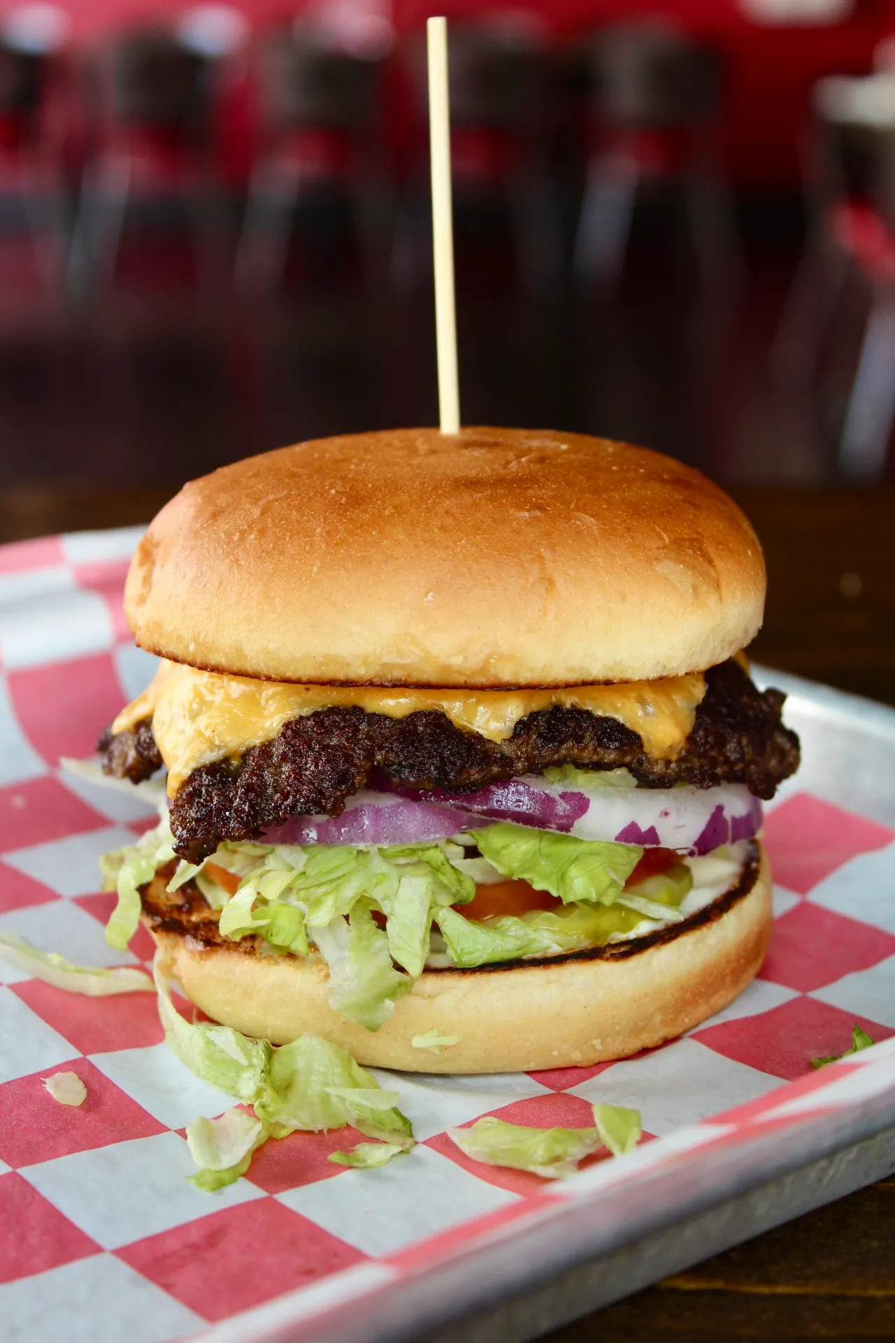 Smashburger A juicy double cheeseburger with lettuce, tomato, and red onion on a checkered paper tray.